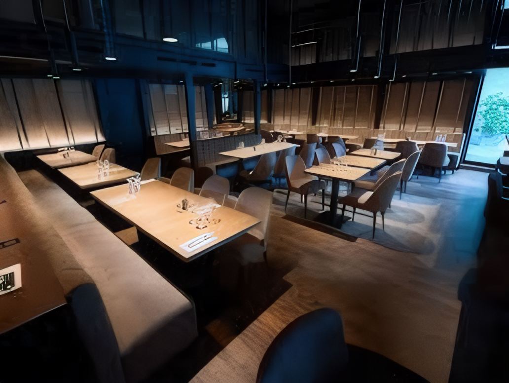 La salle : banquettes, tables en bois clair, fauteuils gris et grandes baies