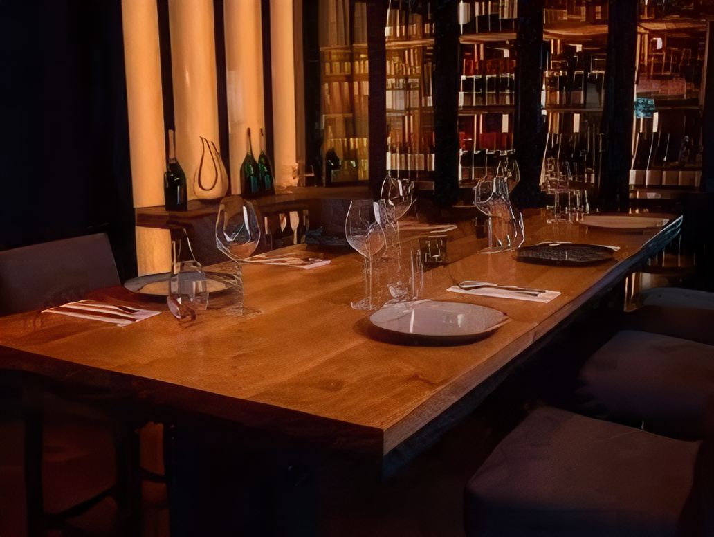 Une table dressée devant le mur de bouteilles éclairé